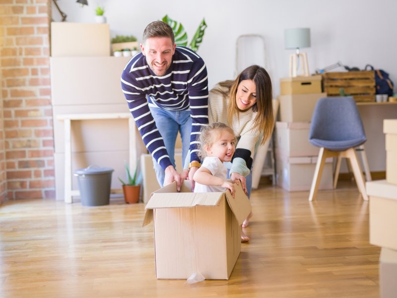 Parents playing with child in a new home with laminate flooring