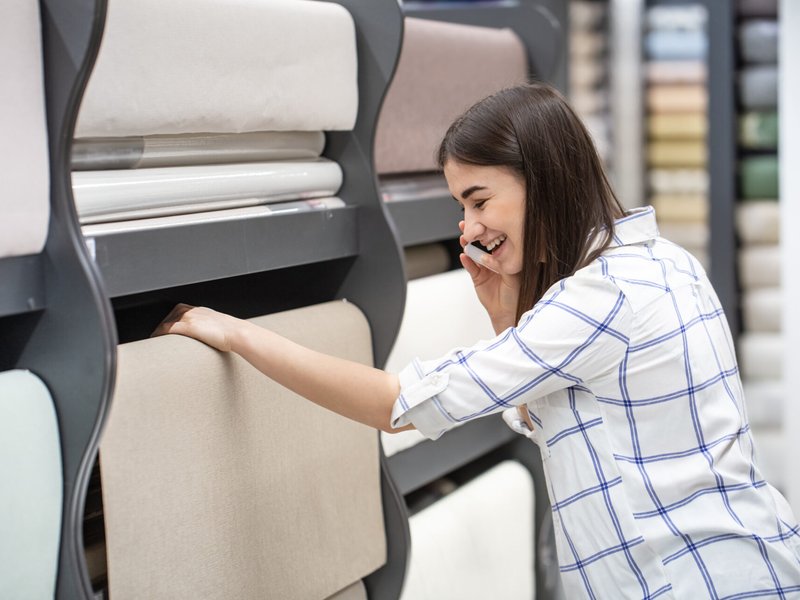 Young woman in a store chooses wallpaper for her home